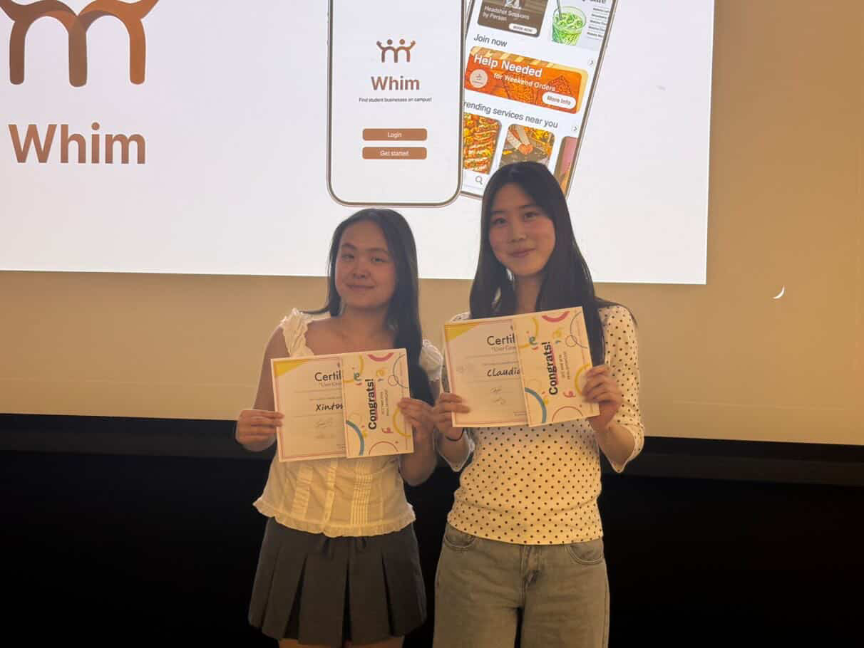 Xintong and her teammate holding certificates in front of the Whim presentation slide